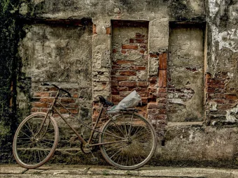 Ein altes Fahrrad lehnt an einer baufälligen Mauer.